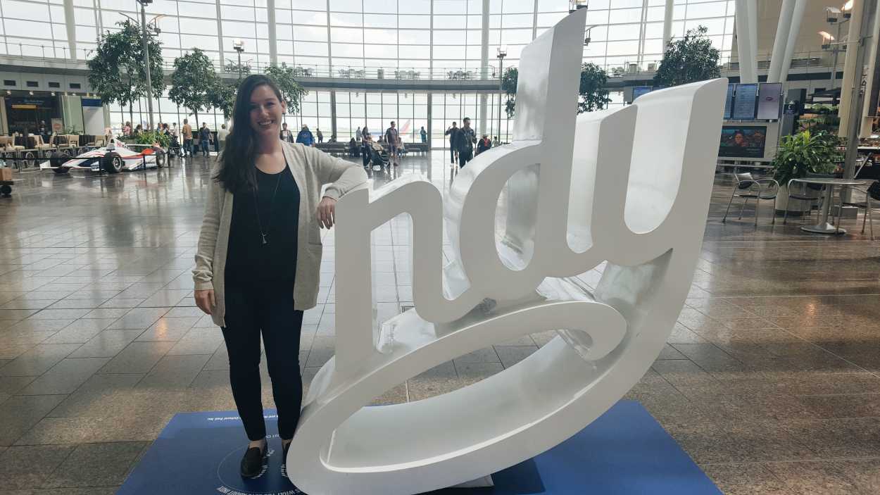 Alyssa stands in front of the "Indy" sign - she is the I