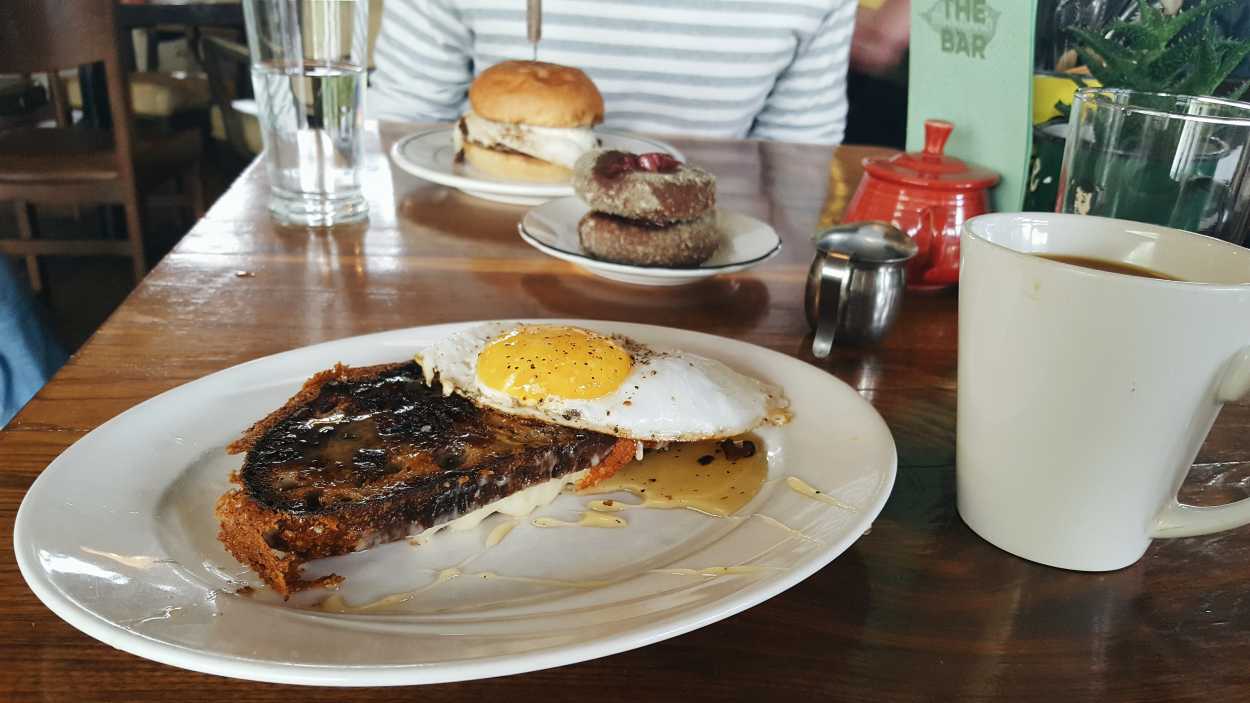 A grilled cheese, fried egg, sweet potato donuts, and a steakburger on a table