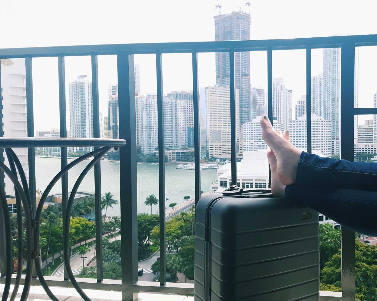 Alyssa rests her feet on an Away suitcase on a balcony in Miami