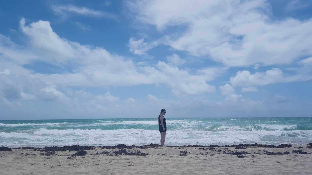 Alyssa stands on Miami Beach which has a lot of seaweed