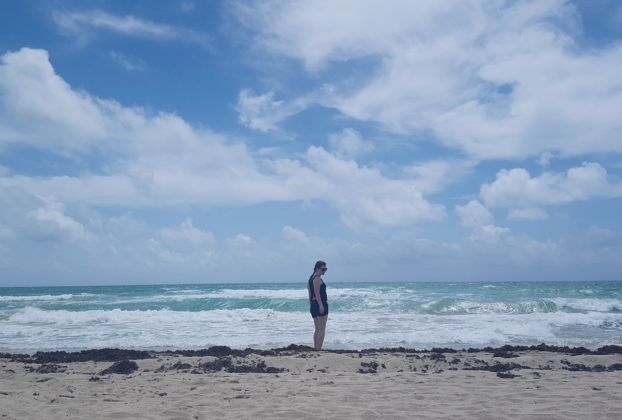 Alyssa stands on Miami Beach which has a lot of seaweed