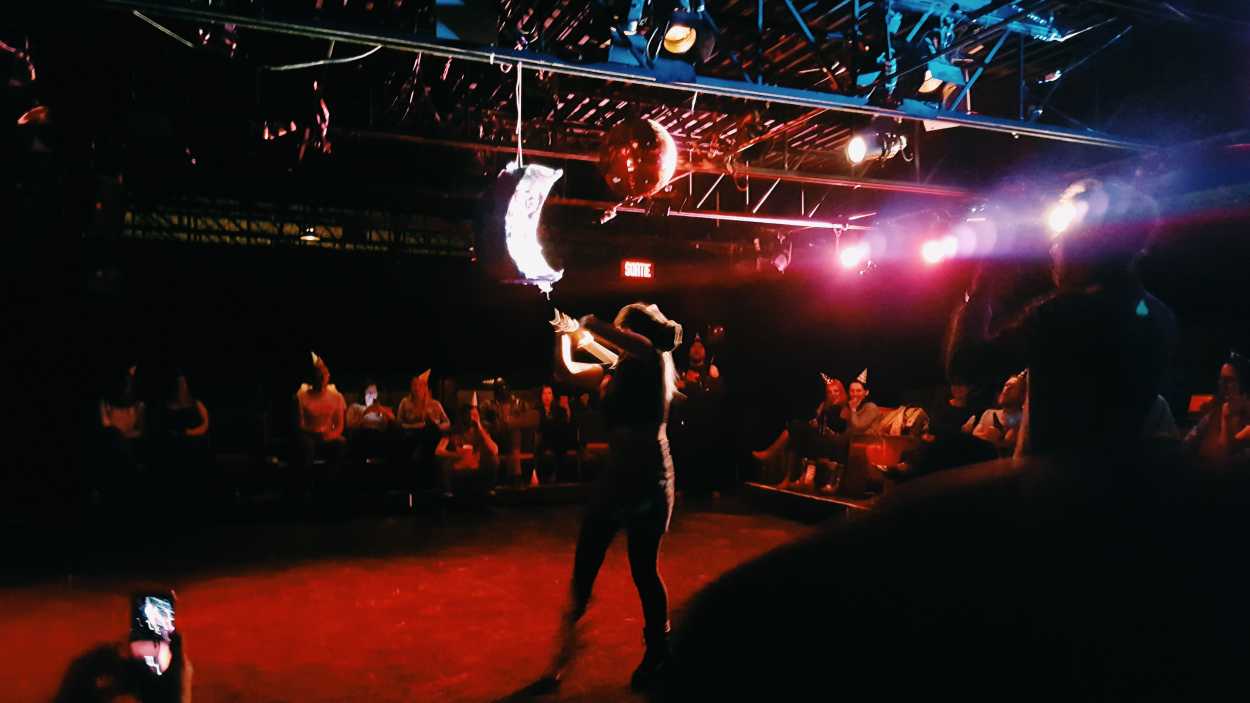 A woman swings at a pinata using a hockey stick