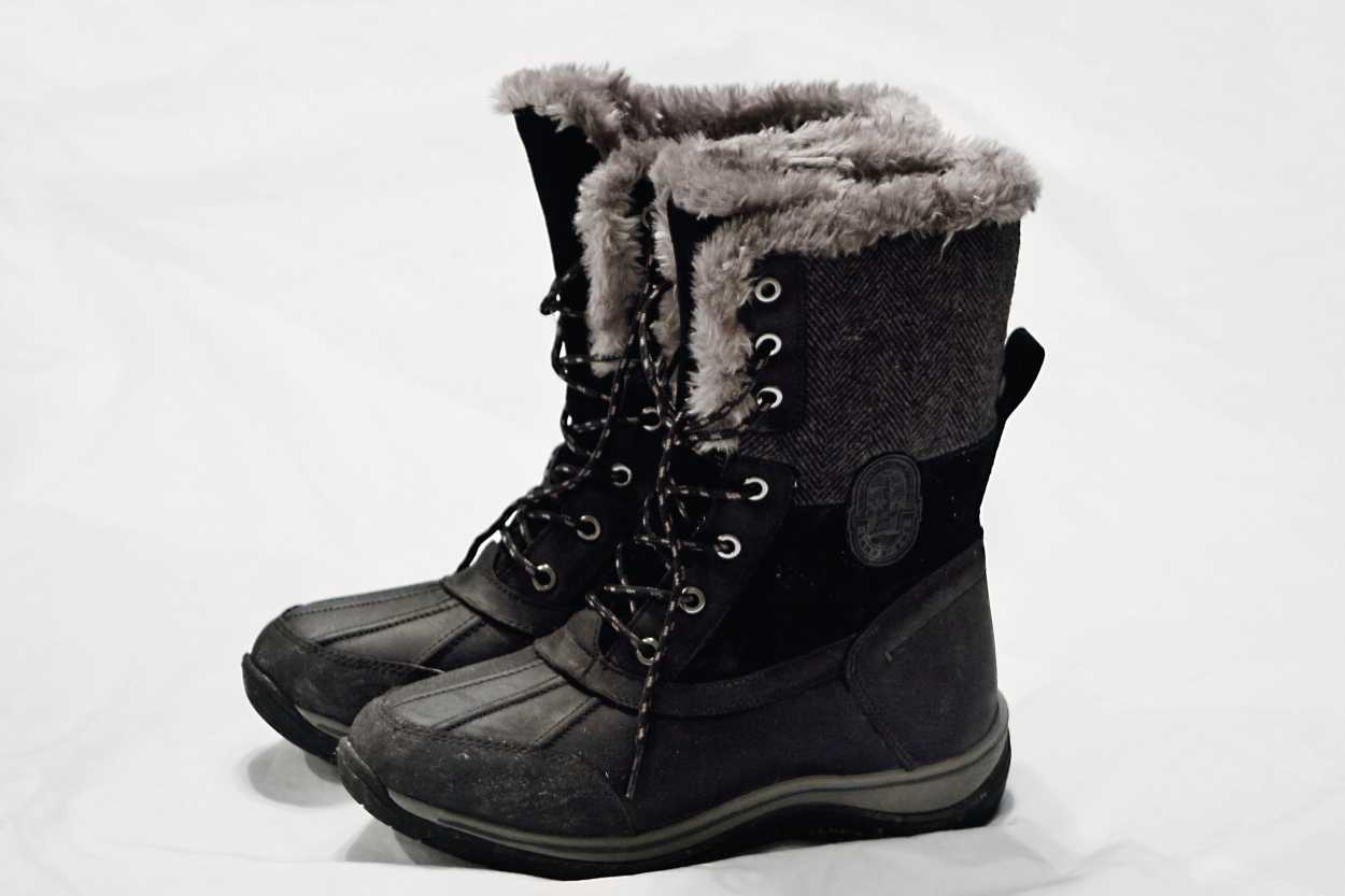 A pair of lace up snow boots on a white sheet
