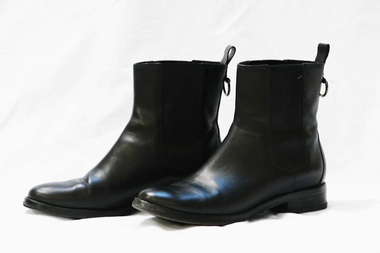 A pair of black Chelsea boots on a white sheet