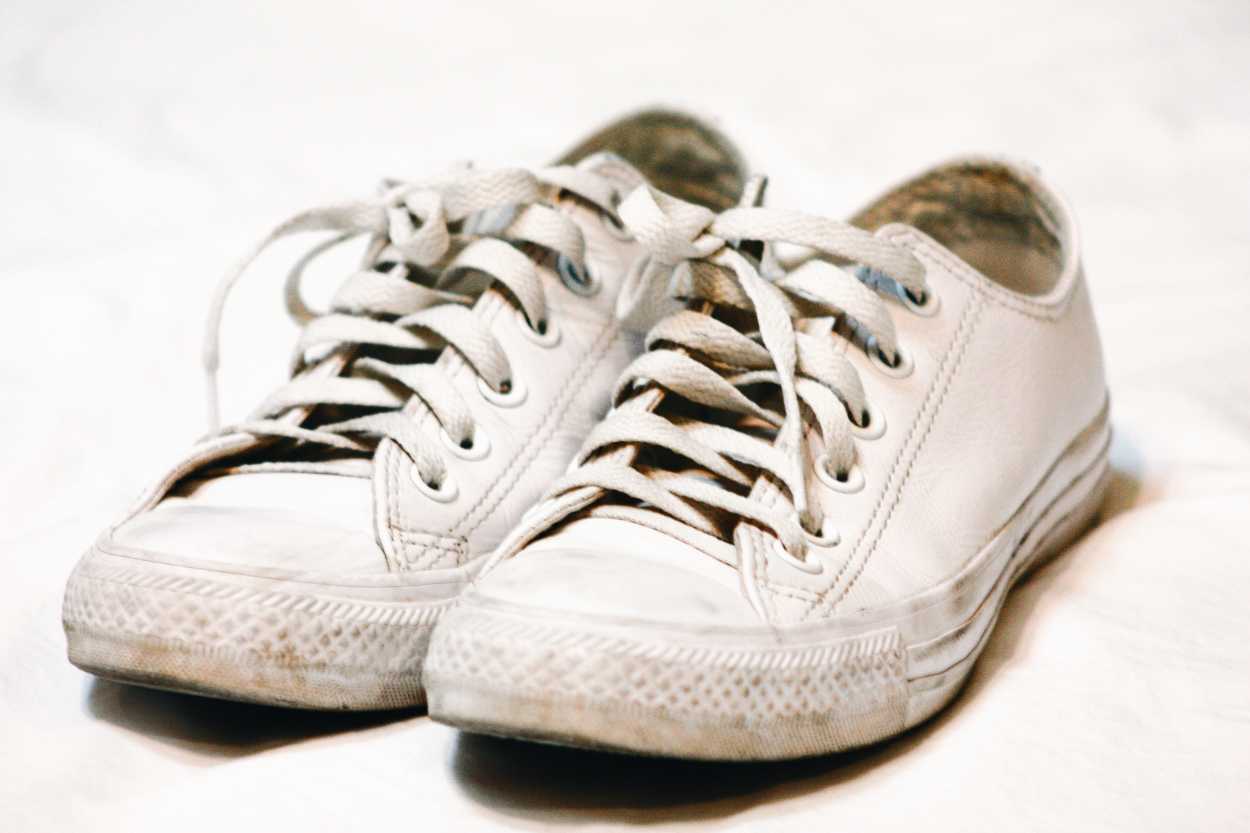 A pair of white Converse low-top sneakers on a white sheet
