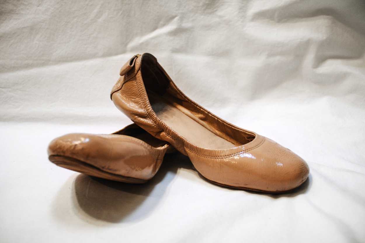 A pair of nude ballet flats on a white sheet