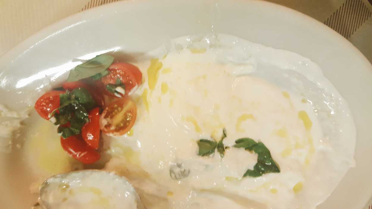 A plate of oozing burrata cheese with olive oil and tomatoes from da Enzo
