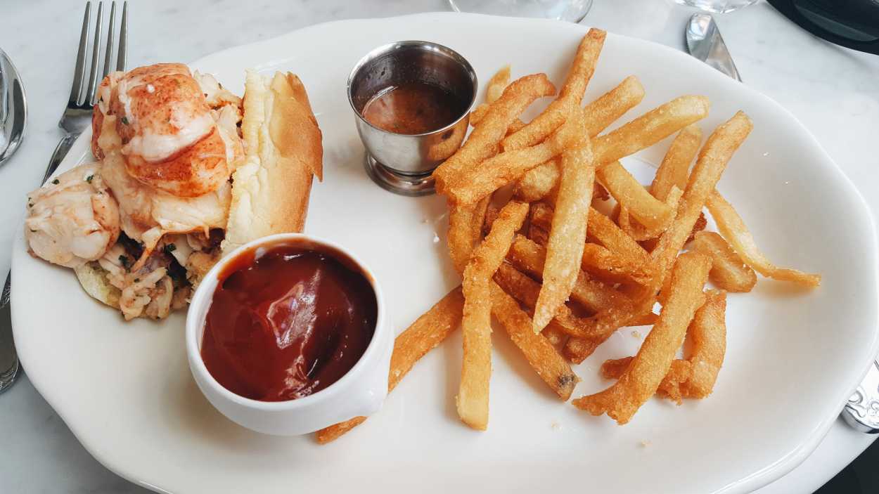 A plate with a half-lobster roll and fries