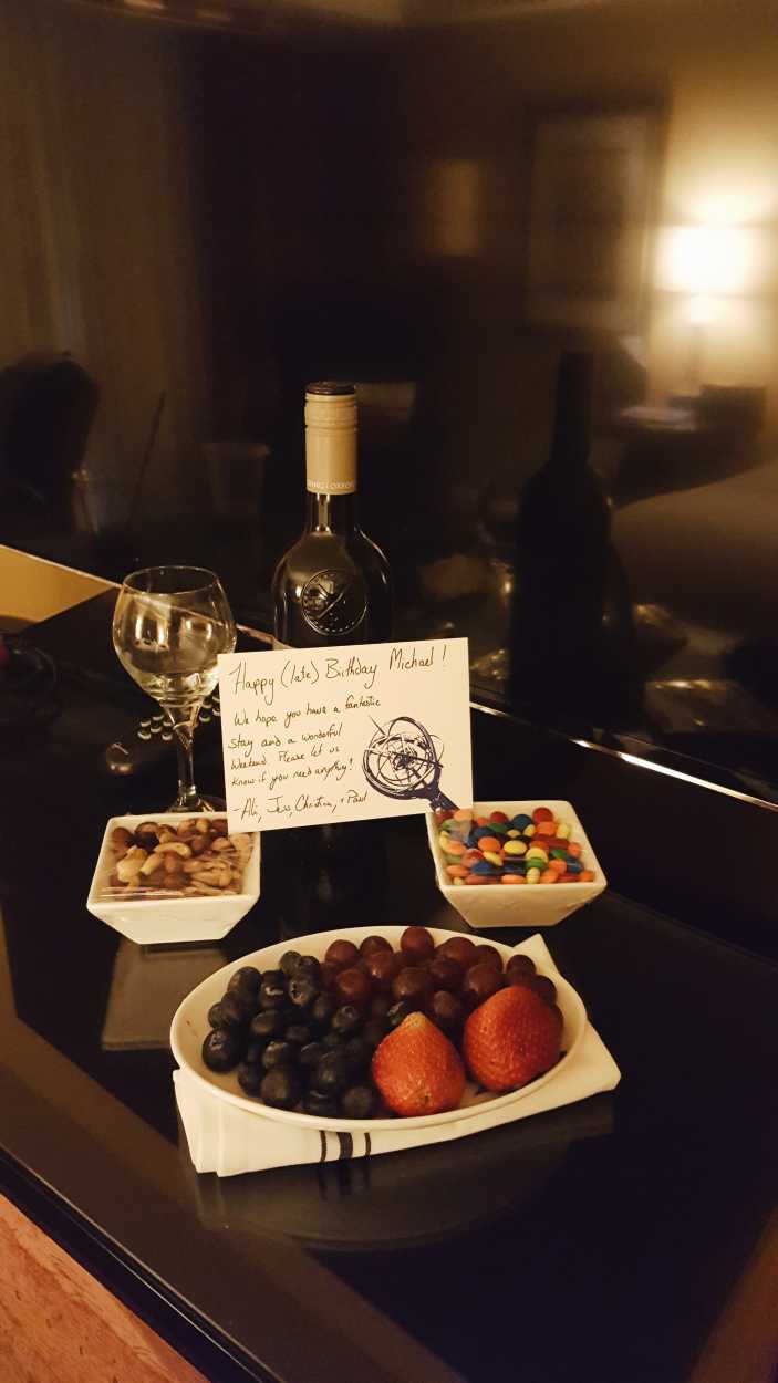 A welcome bottle of wine, fruit, nuts, and candies from a hotel