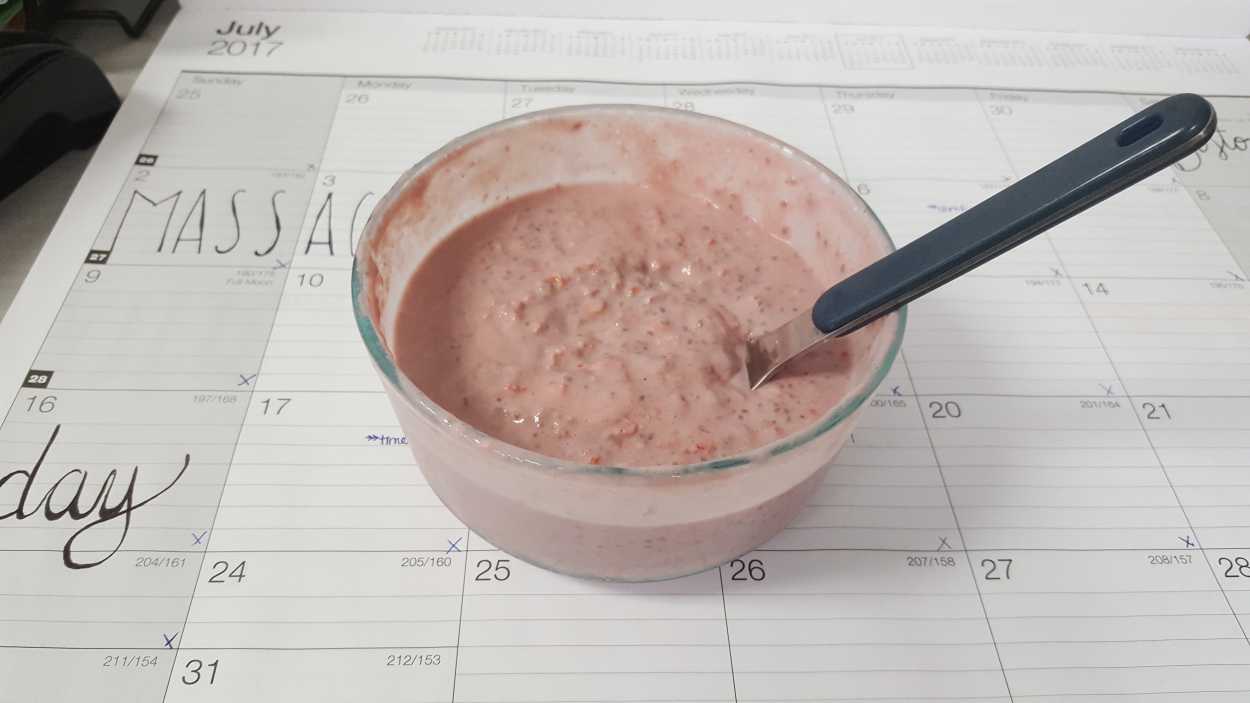 A bowl of Strawberry Rosemary Overnight Chia Oatmeal sits on top of a desk calendar