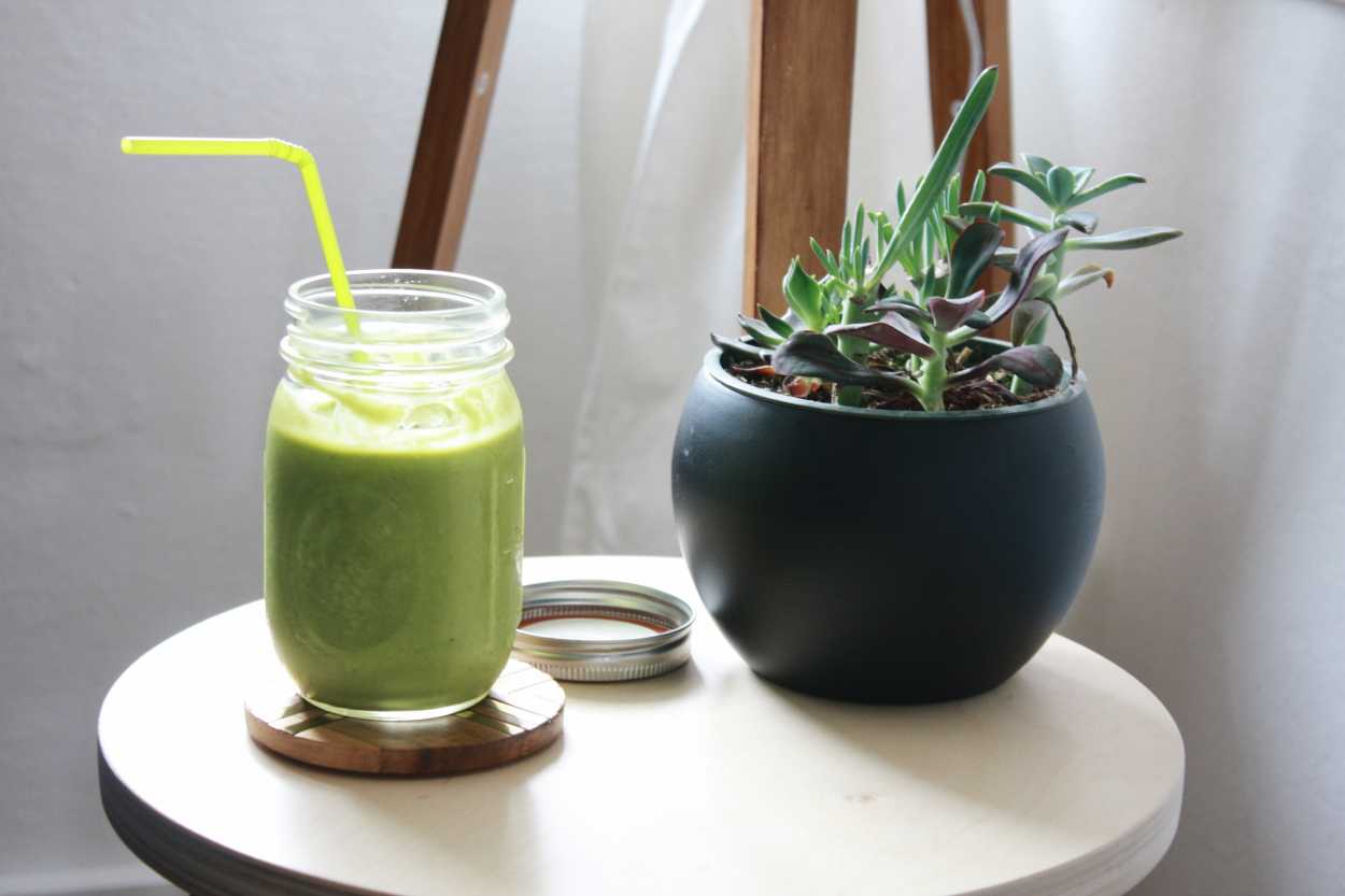 A green smoothie sits next to a succulent