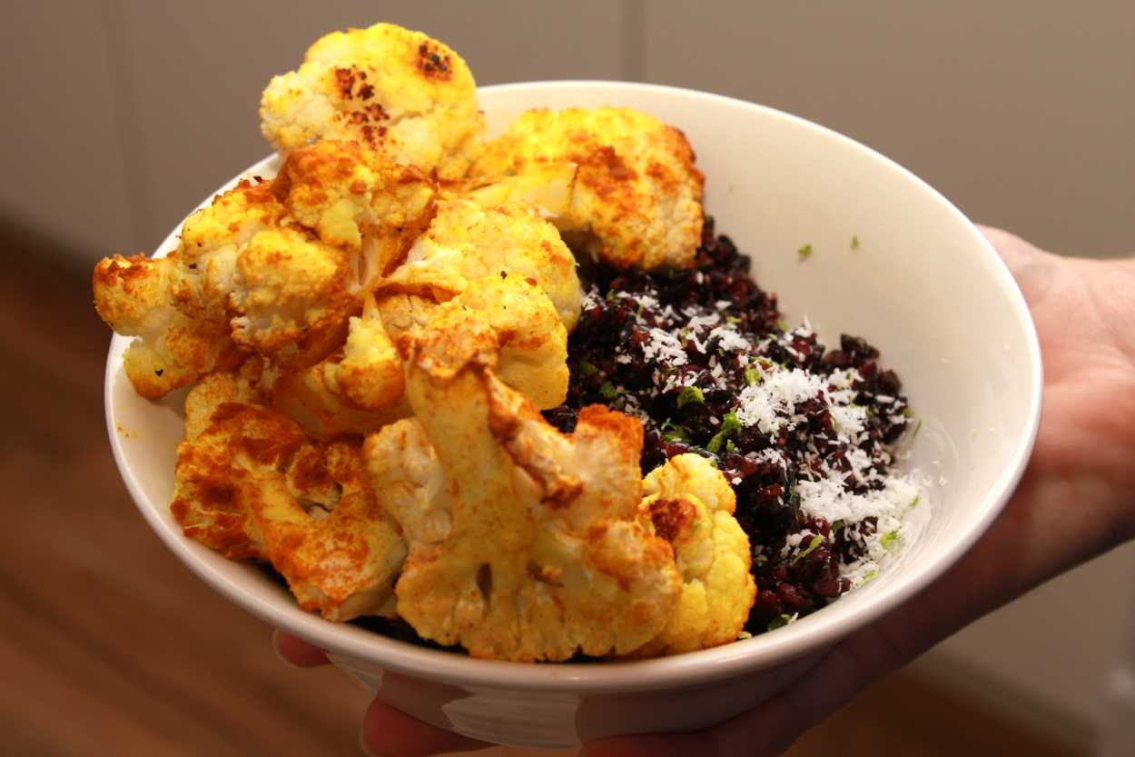 A white bowl of Turmeric-Roasted Cauliflower with Coconut Lime Forbidden Rice