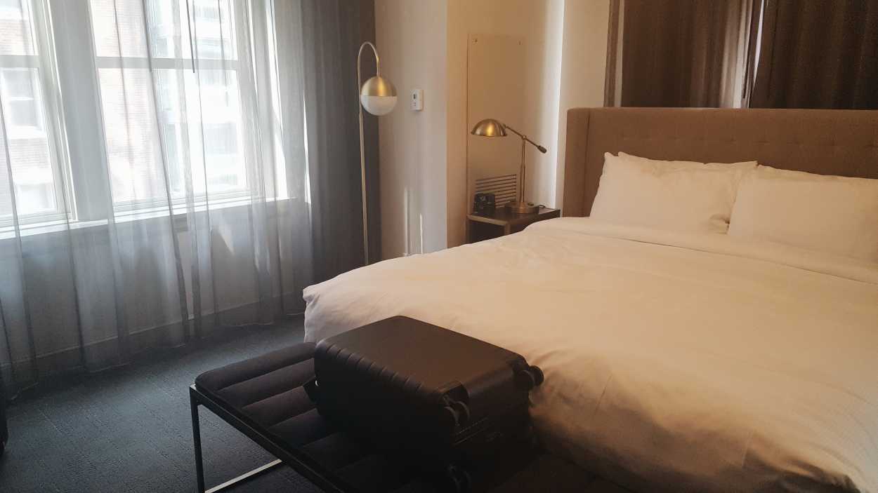 An Away suitcase in front of a King bed
