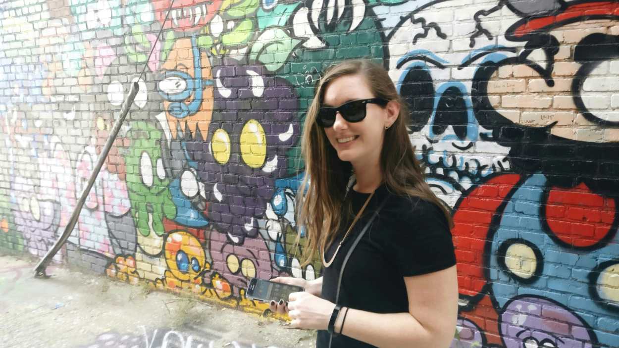 Alyssa stands in an alley with video game graffiti