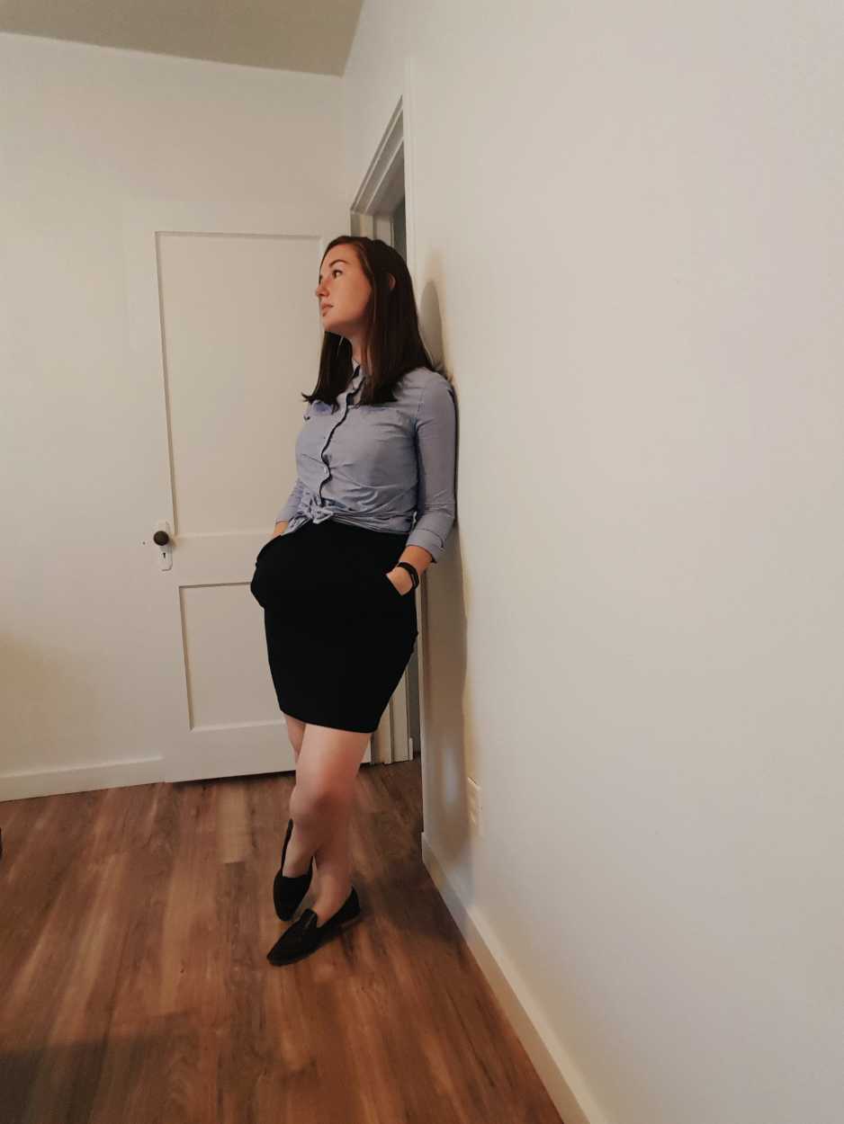 Alyssa wears a blue button-down tied in a knot over a black dress with loafers in the evening