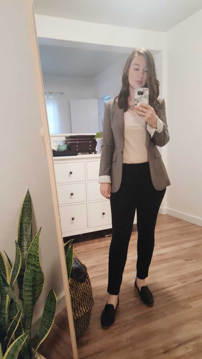 Alyssa takes a selfie wearing a pink tee, black pants, black loafers and gray blazer