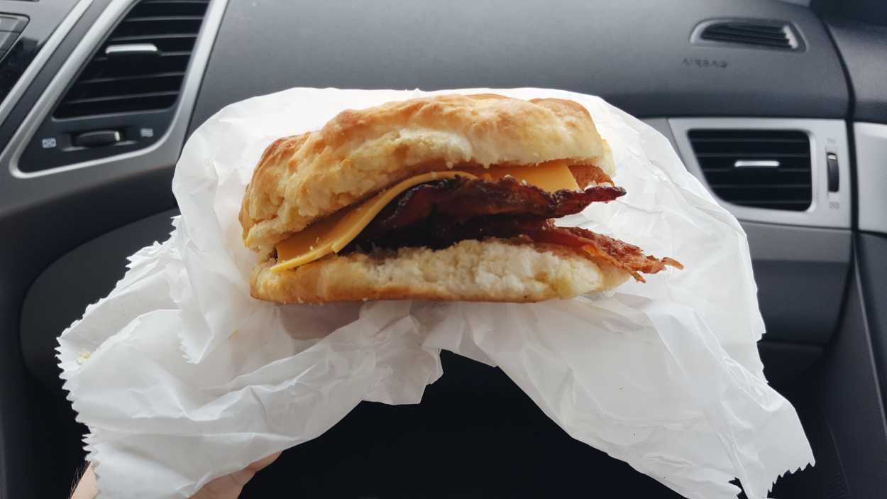 A bacon and cheese biscuit eaten in a car