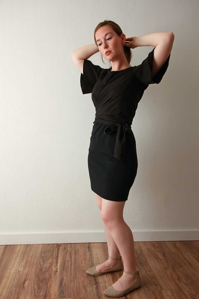 Alyssa wears a black wrap top from Vetta over a black dress with tan shoes
