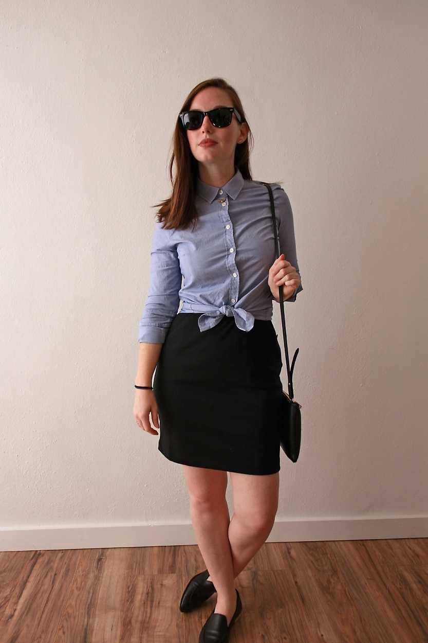 Alyssa wears a blue button-down tied in a knot over a black dress with loafers and sunglasses