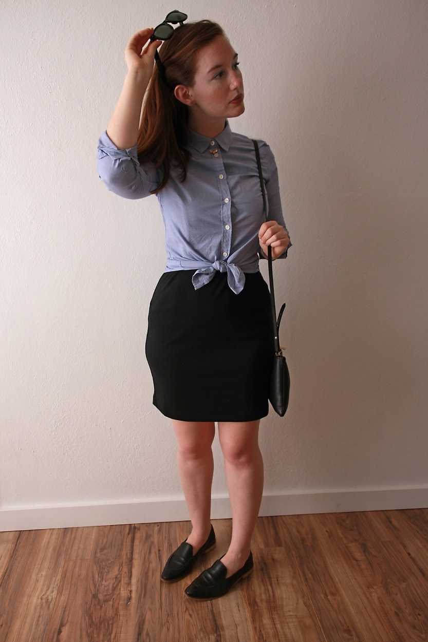 Alyssa wears a blue button-down tied in a knot over a black dress with loafers and sunglasses