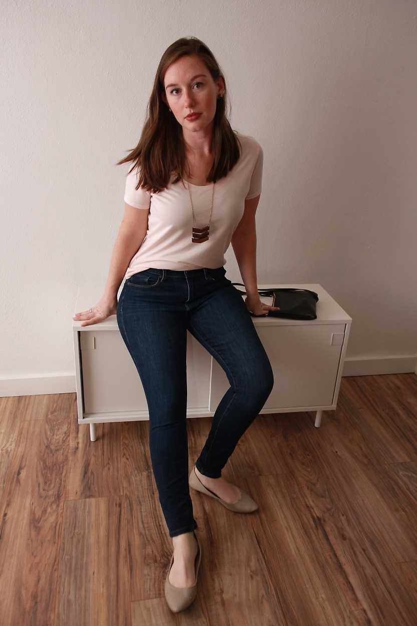 Alyssa wears a blush tee, blue jeans, and nude flats and sits down on a bench