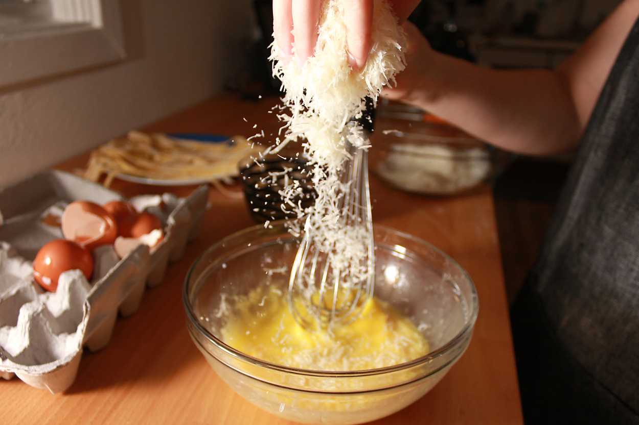 Alyssa drops grated cheese into beaten eggs