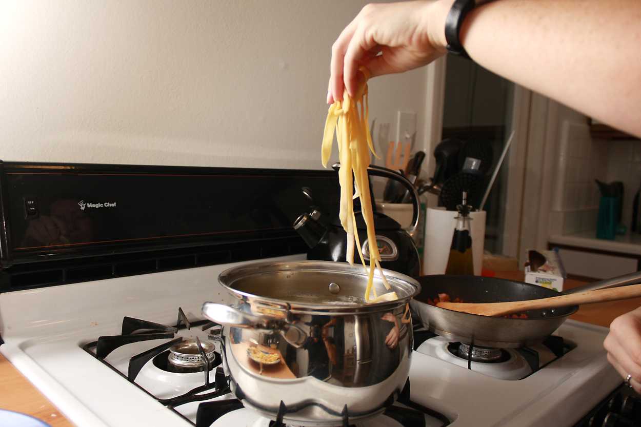 Alyssa drops noodles into a pot of boiling water