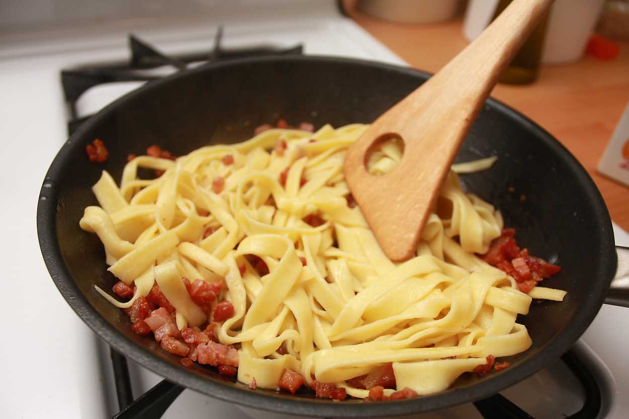 Alyssa stirs the noodles with pancetta