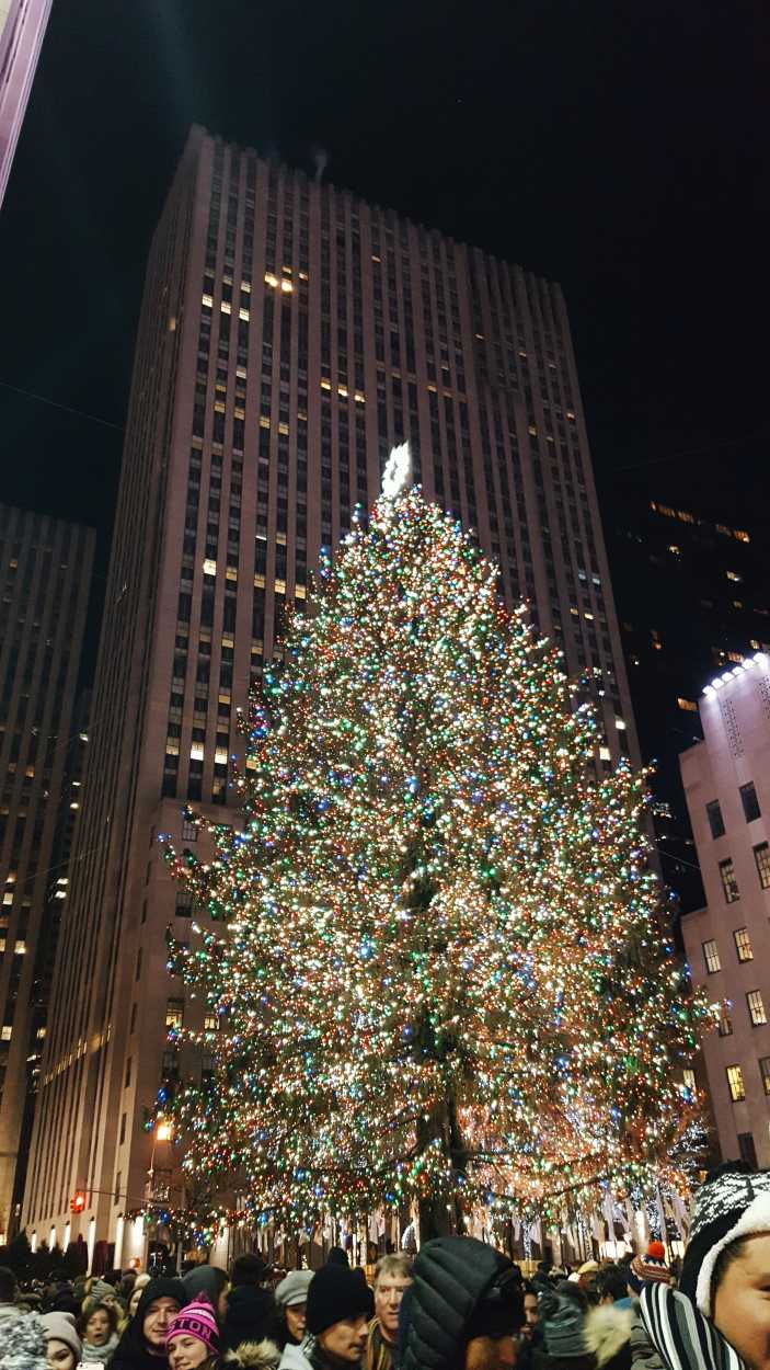 A crowd of people in front of the Rockefeller Christmas Tree