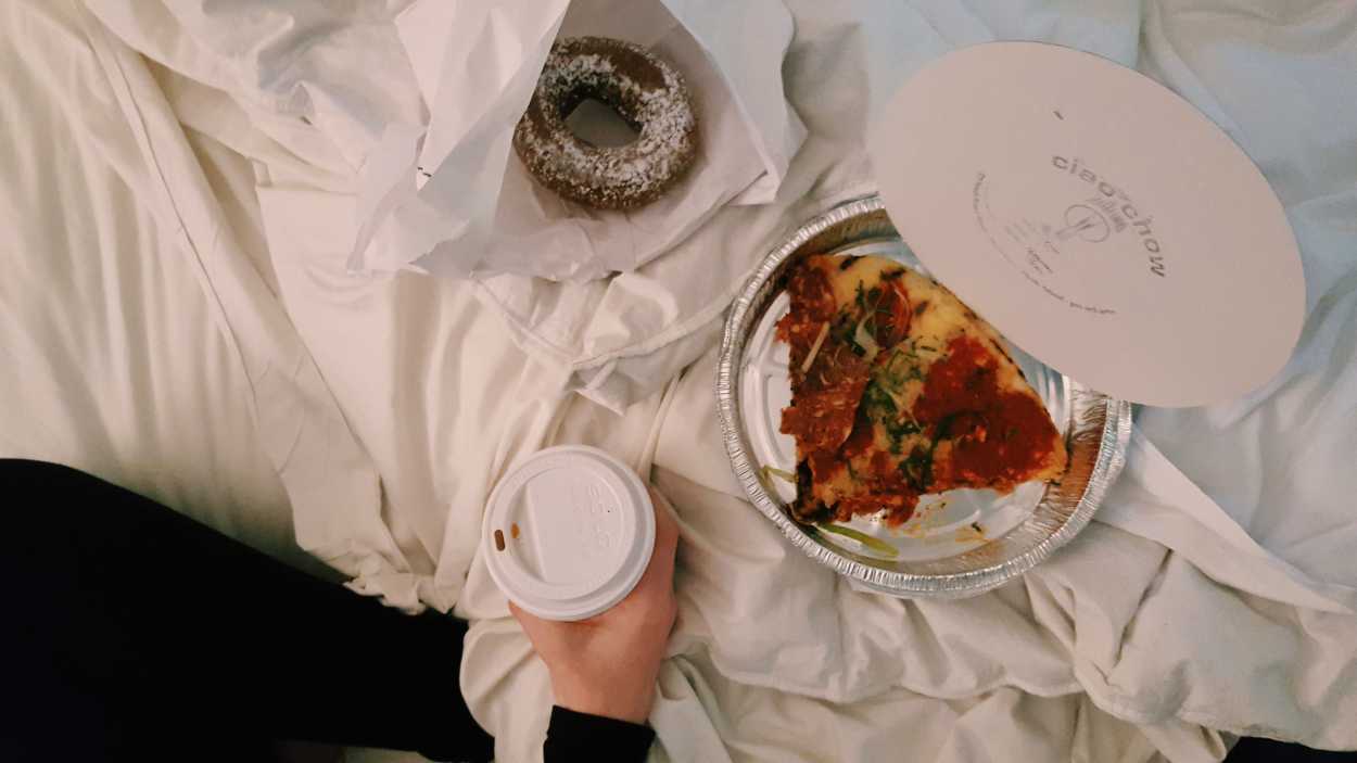 Alyssa eats pizza and doughnuts in bed