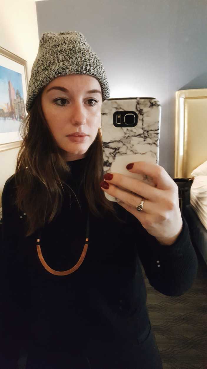 Alyssa wears a beanie and black turtleneck and takes a mirror selfie
