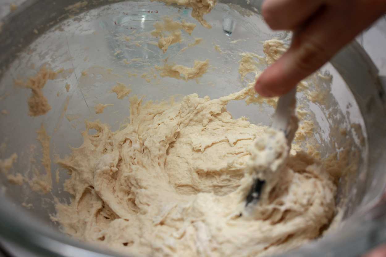 Alyssa stirs the bagel dough sponge with a spatula