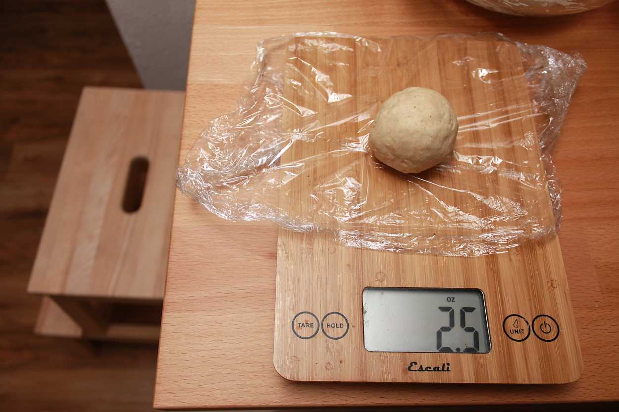 weighing a 2.5 oz ball of dough on a kitchen scale