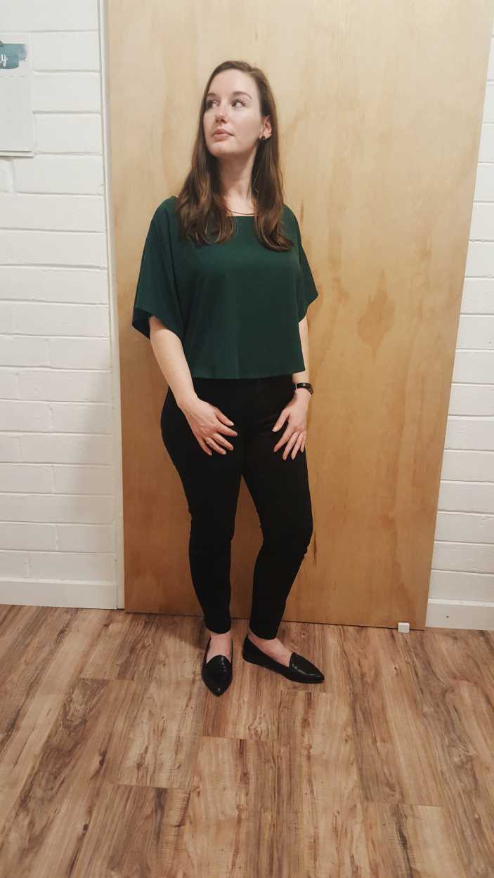 Alyssa wears a green top, black jeans, and black flats in the evening