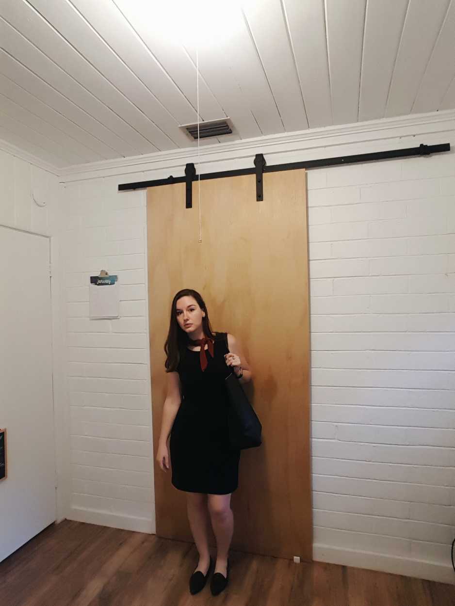 Alyssa wears a black sheath dress with black flats and a rust bandana in the evening