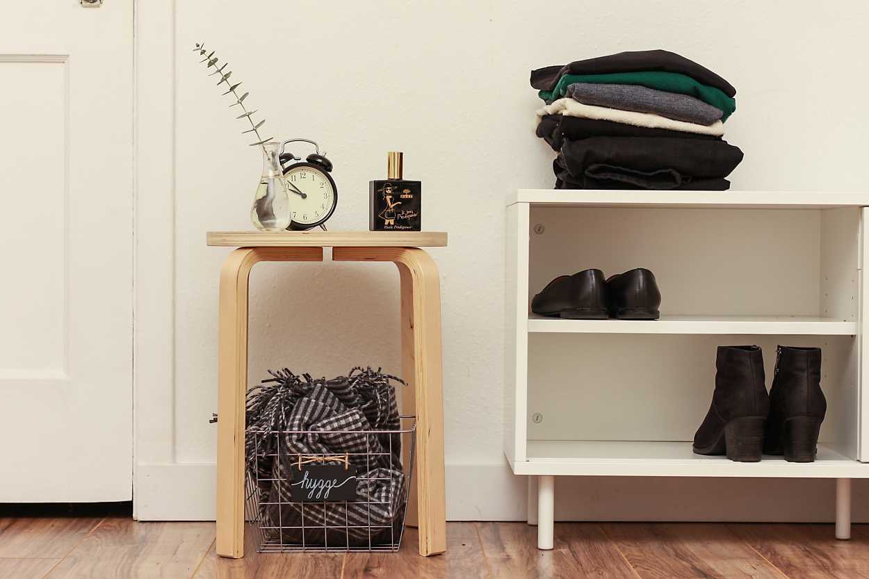 A stack of clothing on a bench with shoes inside