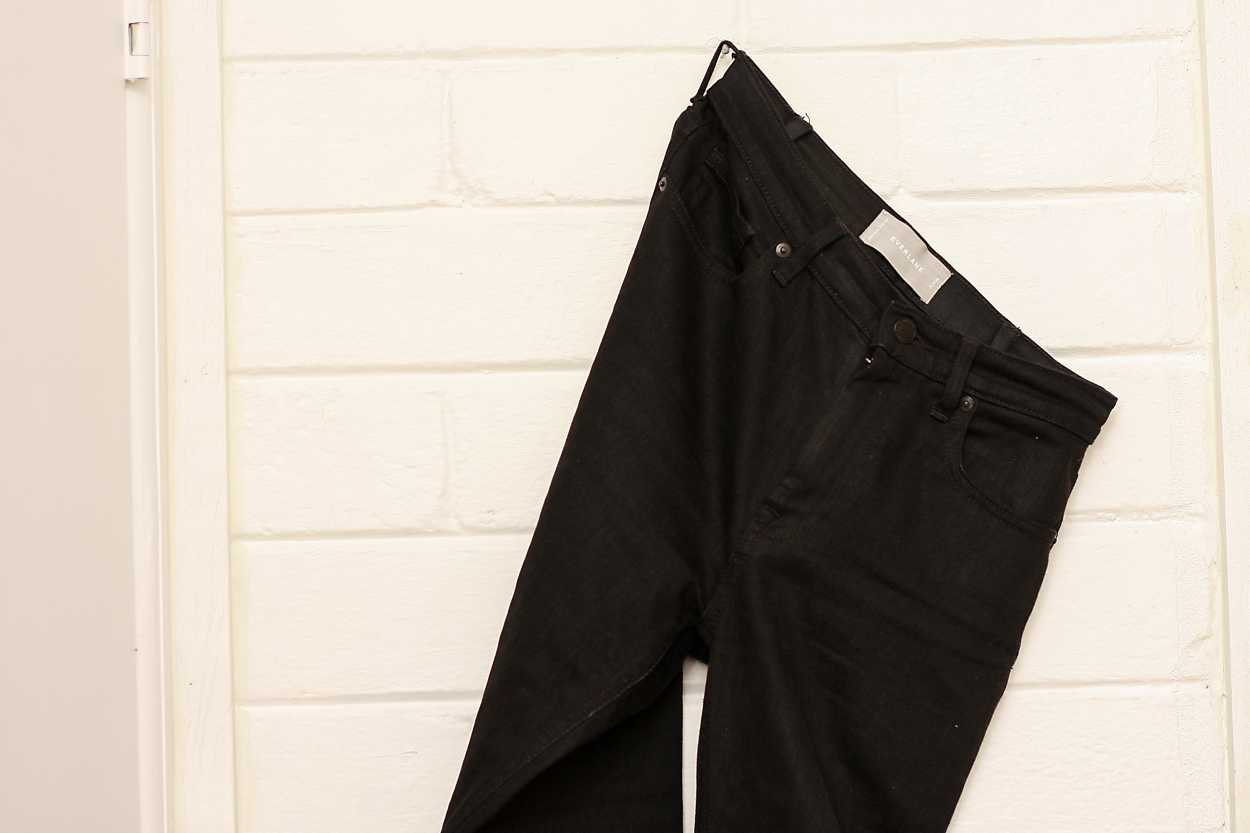 A pair of Everlane's high rise skinny jeans hanging from a peg