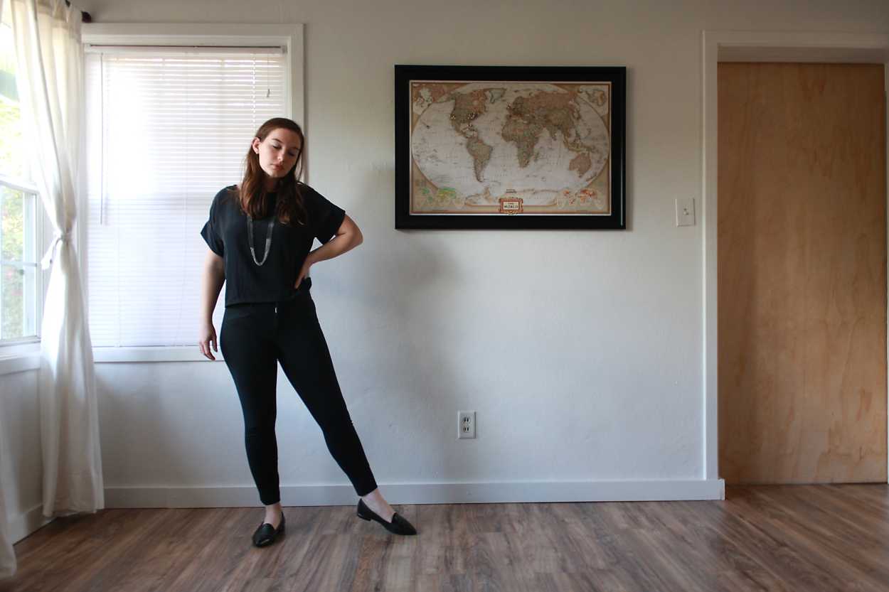 Alyssa wears a silk tee, black pants, and black flats