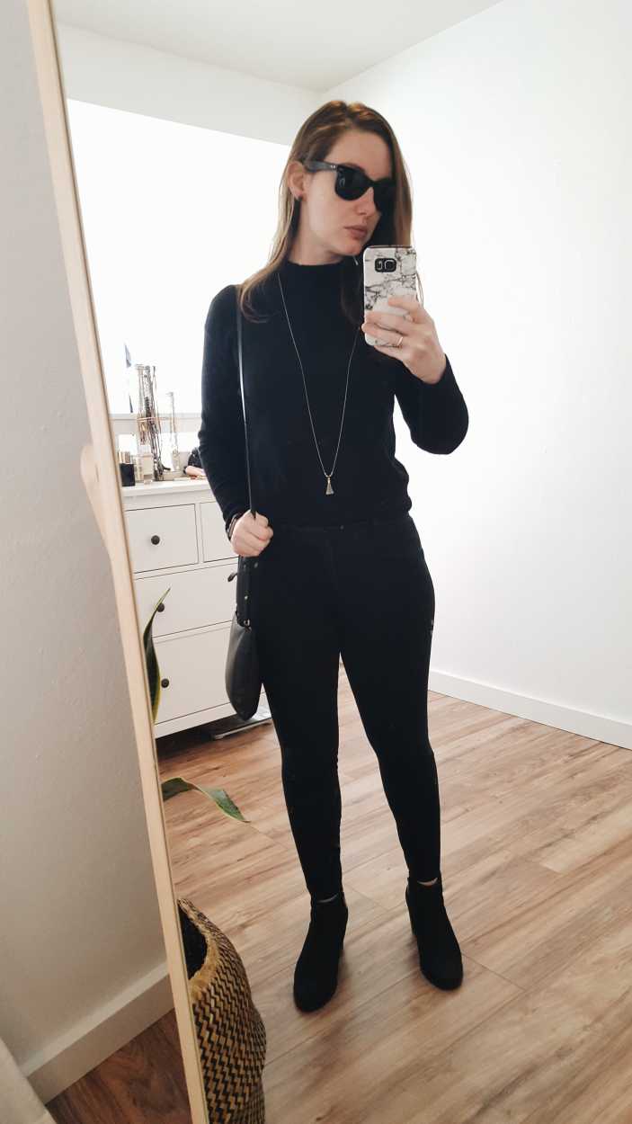 Alyssa wears a black cashmere mockneck sweater with black pants and boots in the morning