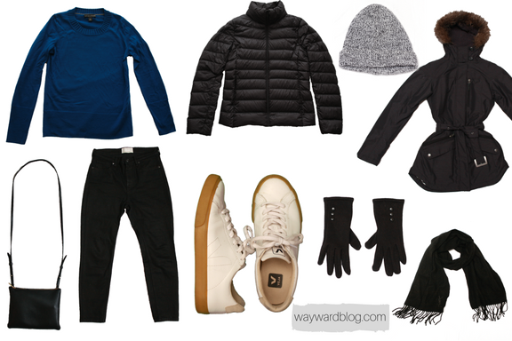 A Winter sightseeing outfit with a blue sweater, black jeans, white sneakers, and black accessories