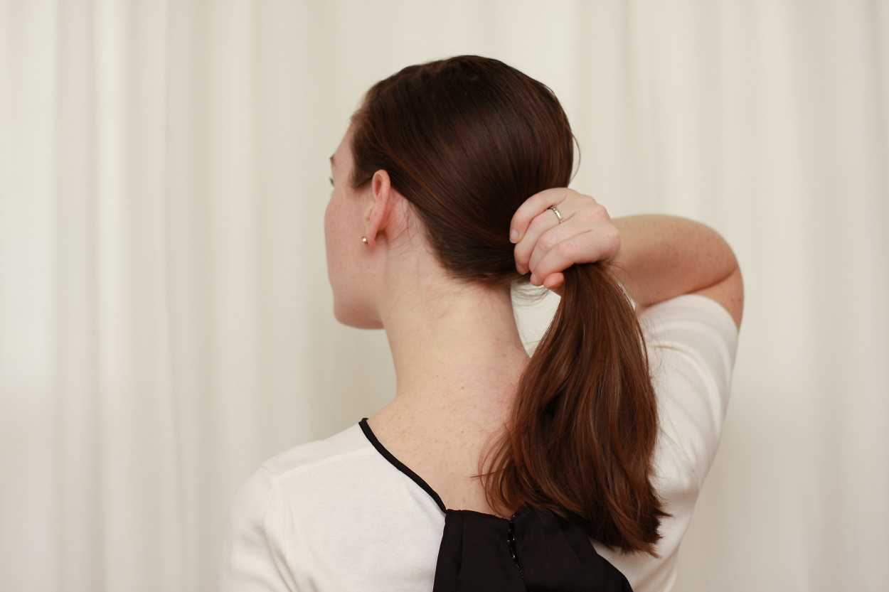 A close up image of hands holding a ponytail