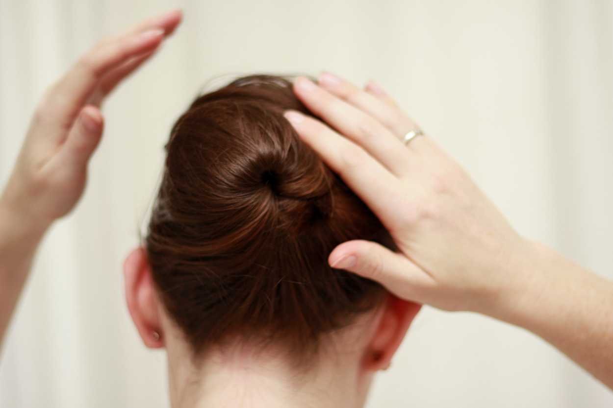 A close up image of hands creating a hair updo