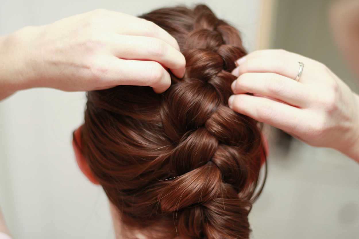 close up of hands adjusting a Dutch braid