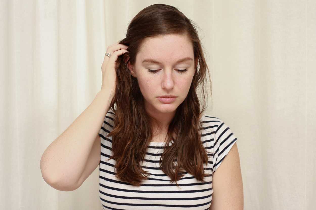 a woman tucks wavy hair behind her ear