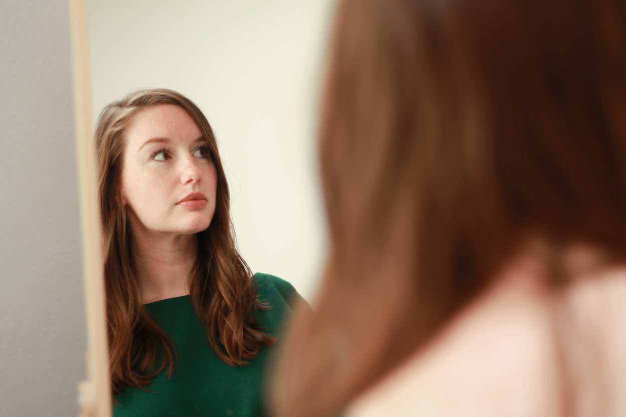 a woman with loose waves is seen in the mirror