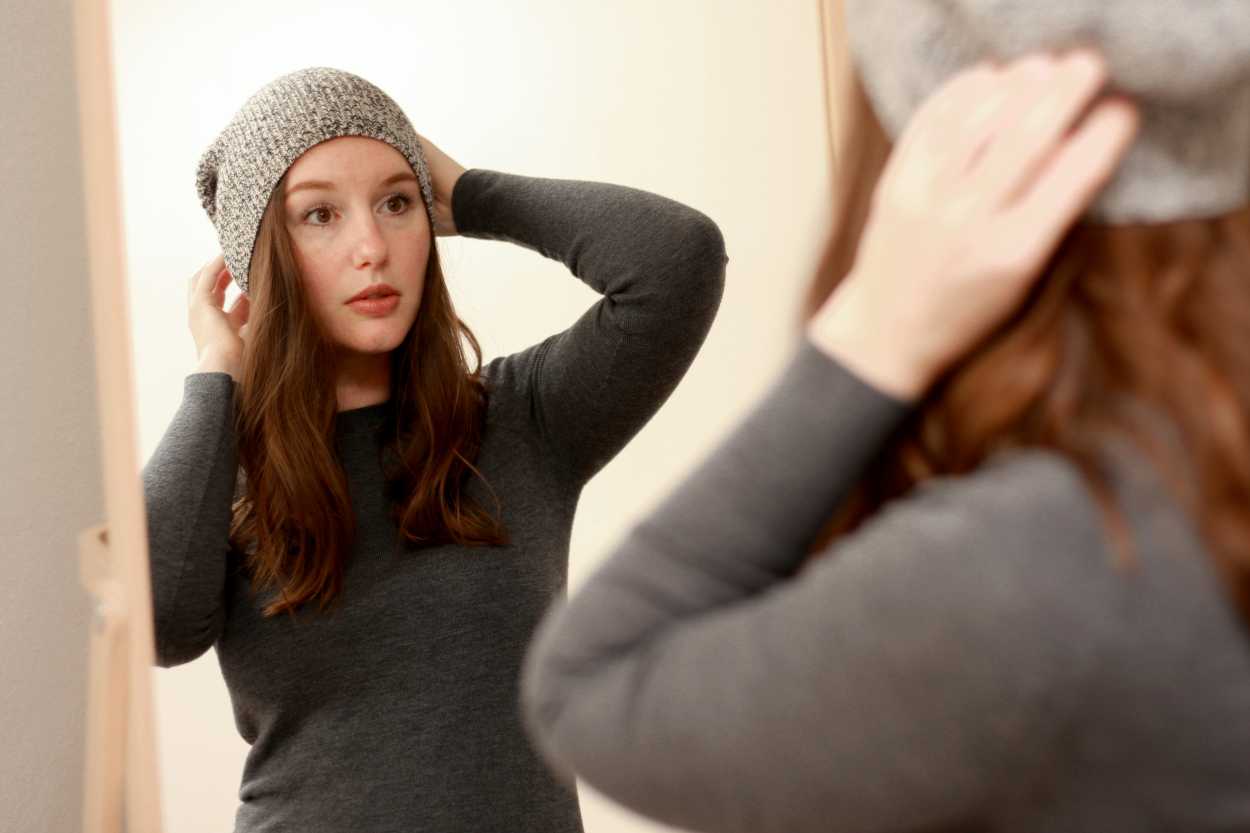 a woman adjusting her hat in the mirror