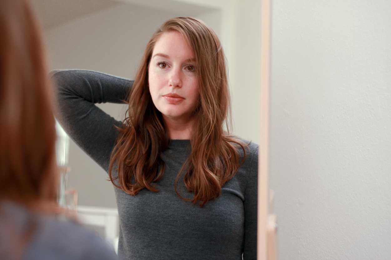a woman adjusting her hairstyle in the mirror