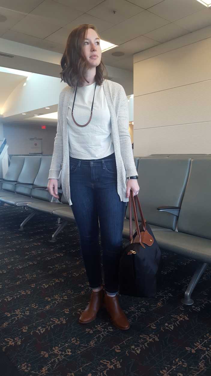 Alyssa wears jeans, boots, and a cardigan in the airport