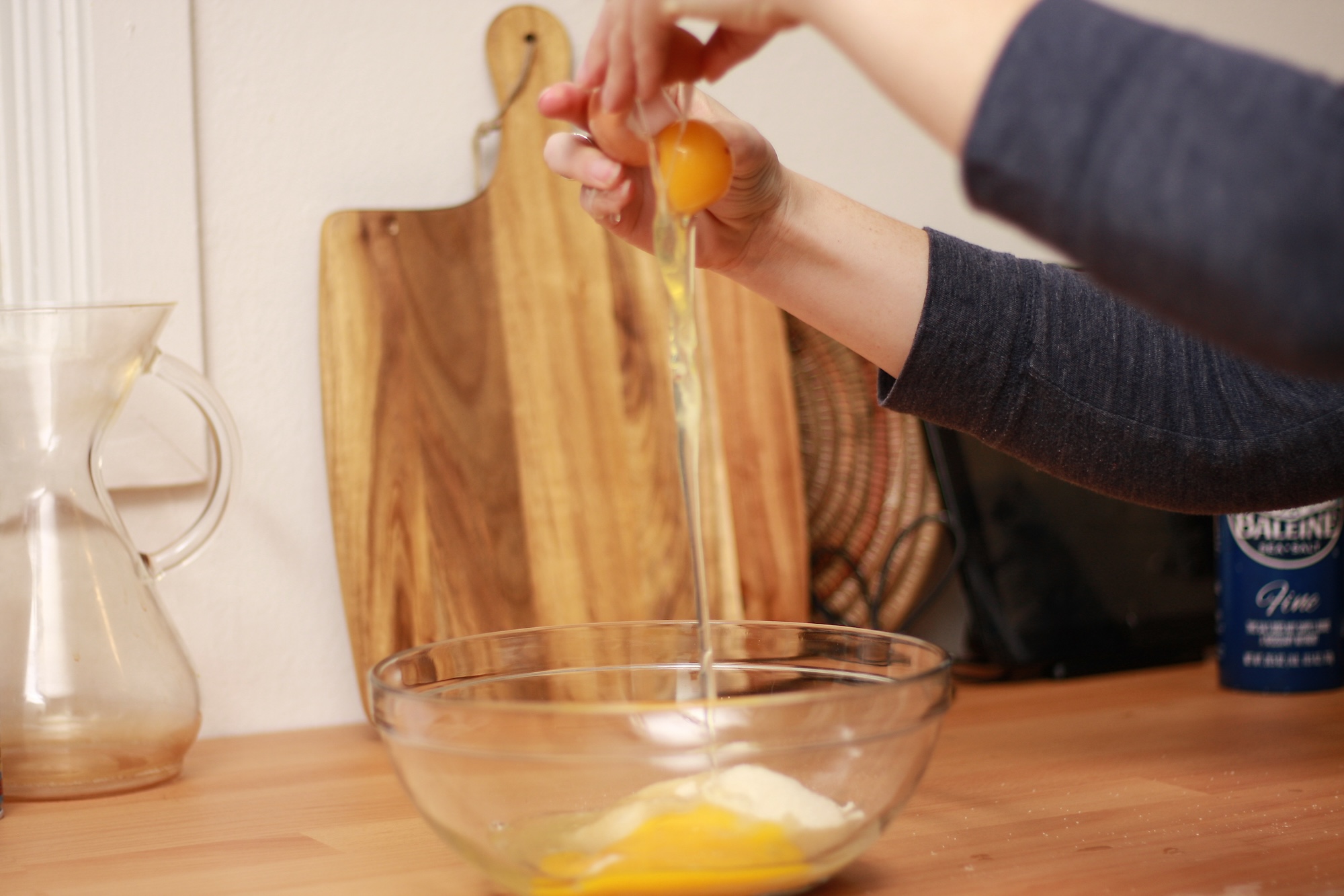 Alyssa cracks an egg into a bowl of sugar