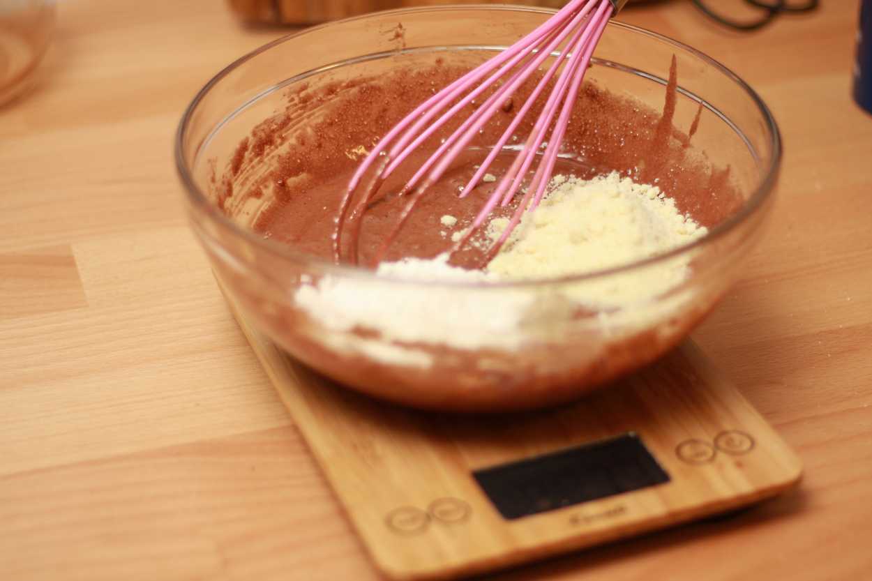 A bowl with cake batter rests on a kitchen scale